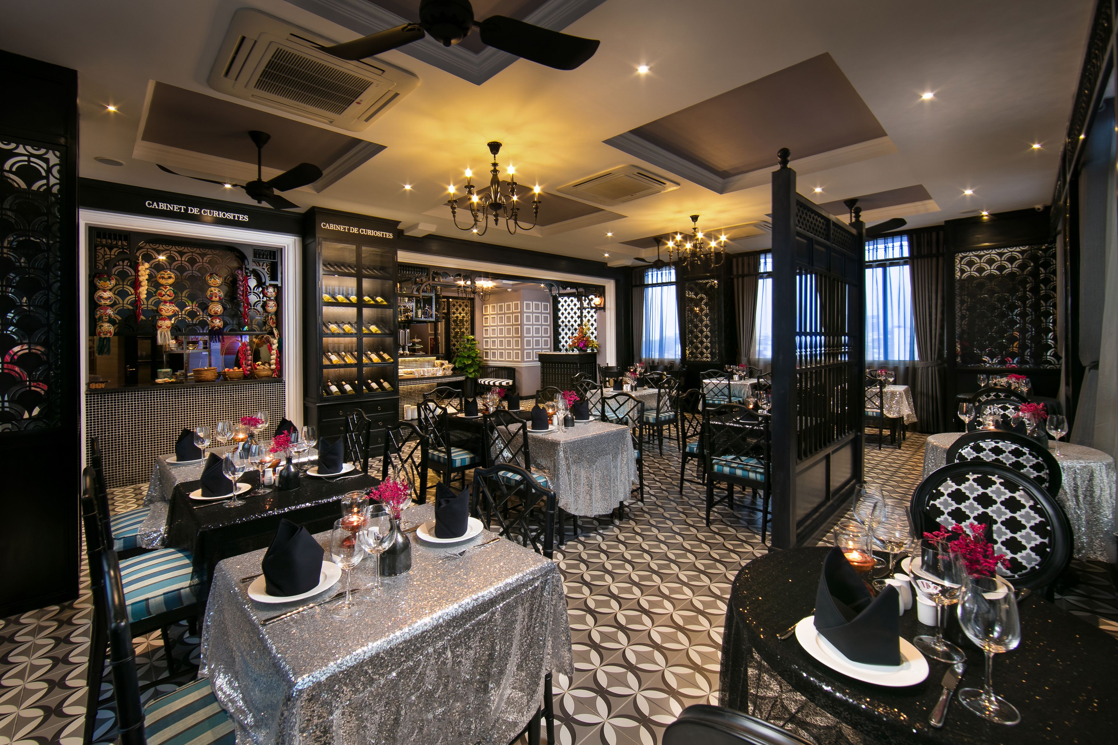 A restaurant with tables set for dining, a shoe display, and a chandelier.