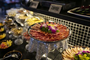 A buffet with various food items, including a central platter of sliced meats and a coffee station.