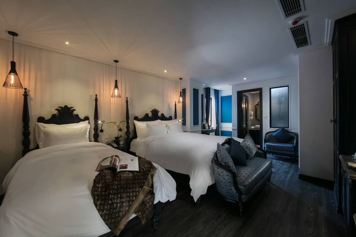 A hotel room with two beds, a sofa, and a small table.