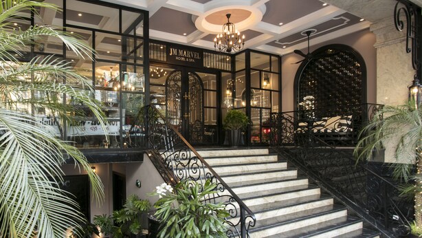 Una imponente escalera con barandales negros que conduce a la entrada de un hotel.