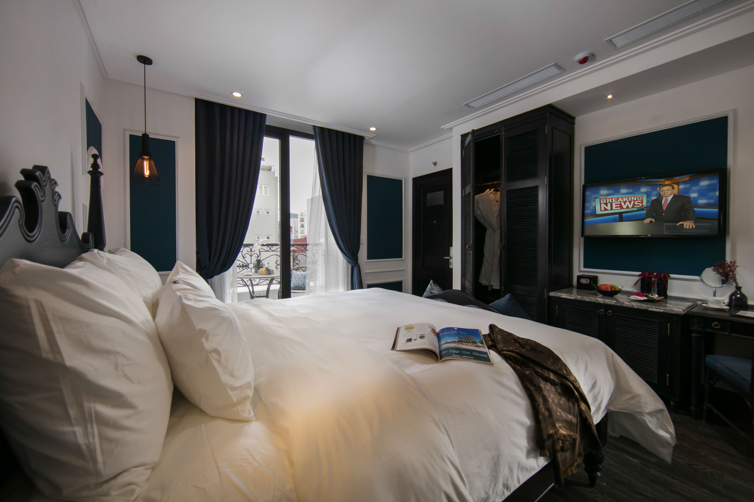 Ett hotellrum med en stor säng, en tv, ett skrivbord och utsikt över staden genom fönstret.