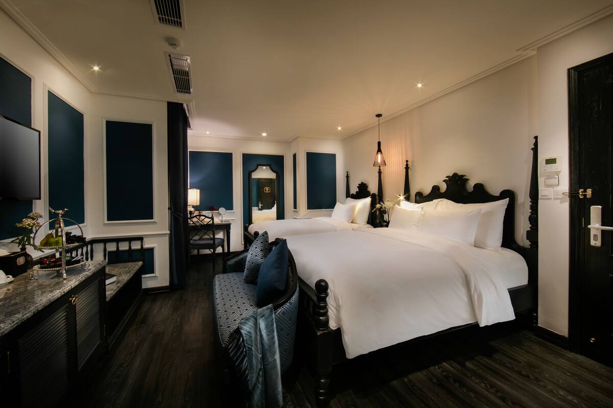 A hotel room with a large bed, a desk with a chair, a vanity, and a mirror.