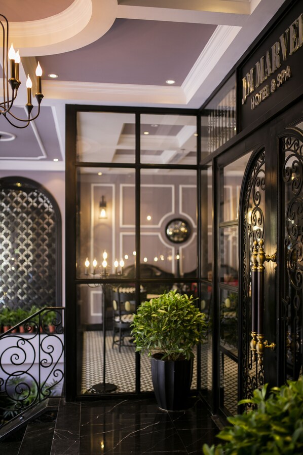 A hotel entrance with a black iron gate, a potted plant, and a chandelier. - JM Marvel Hotel & Spa (Hanoi)