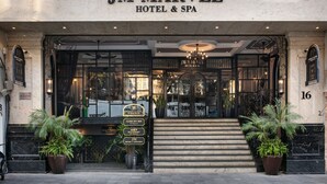 La entrada al Hotel JM Marvel & Spa, con un acceso imponente que incluye escalones, una araña y plantas en macetas.