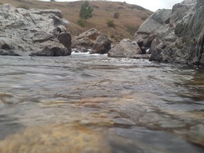 Un río que serpentea entre grandes rocas, con una colina al fondo.