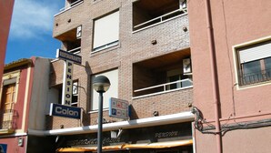 A multi-story building with a brick facade, balconies, and a ground-floor restaurant named 'Colon'. - Pensión Colón (San Juan de Alicante)