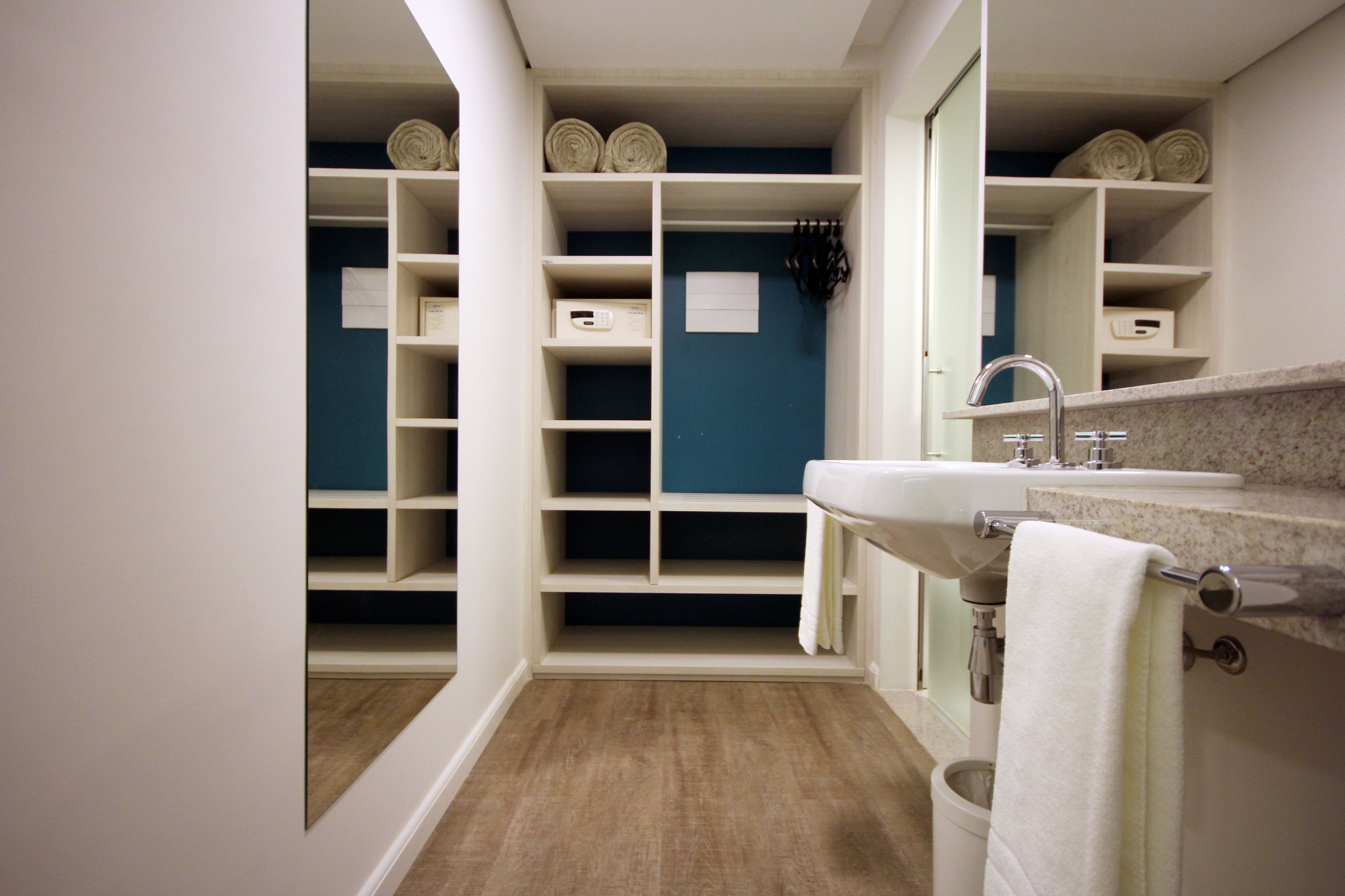 A bathroom with a sink, mirror, and storage shelves.