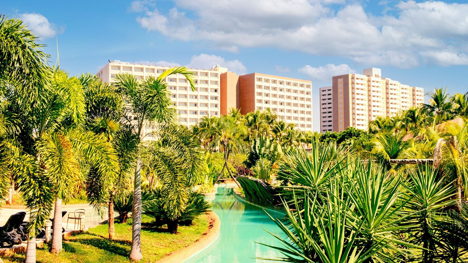 A resort with multiple high-rise buildings, a swimming pool, and lush greenery.