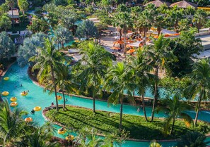 Un resort con varias piscinas, palmeras y zonas de estar al aire libre.
