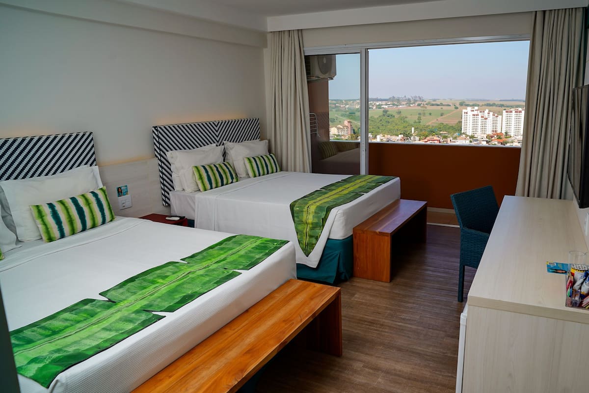 Une chambre d’hôtel avec deux lits, un bureau et une vue sur la ville.