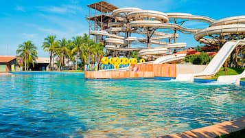 Enjoy the vibrant water park with multiple water slides and a large pool, surrounded by a wooden deck with seating and a covered area.