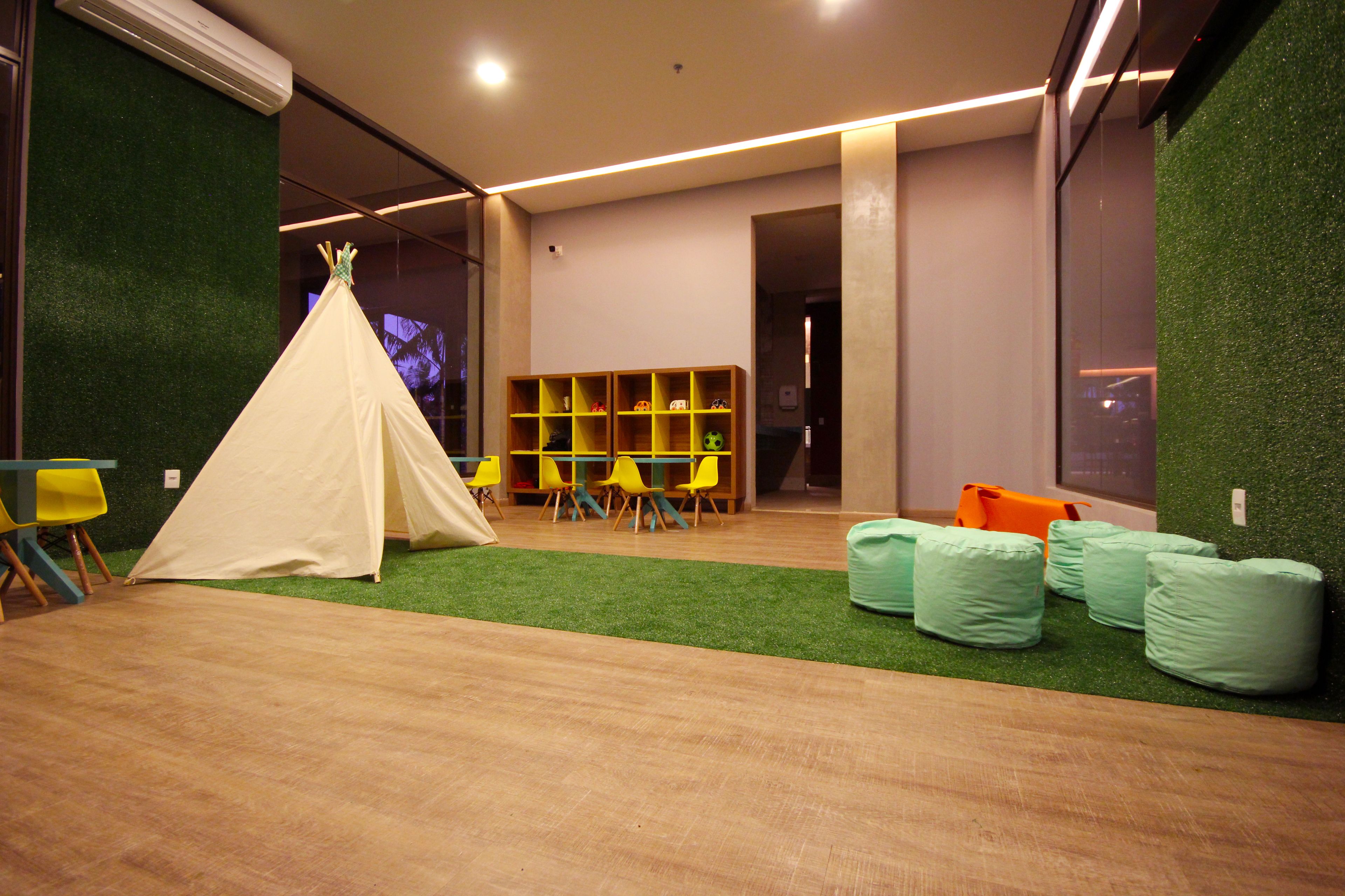 A room with a tent, yellow chairs, a bookshelf, and green bean bags.