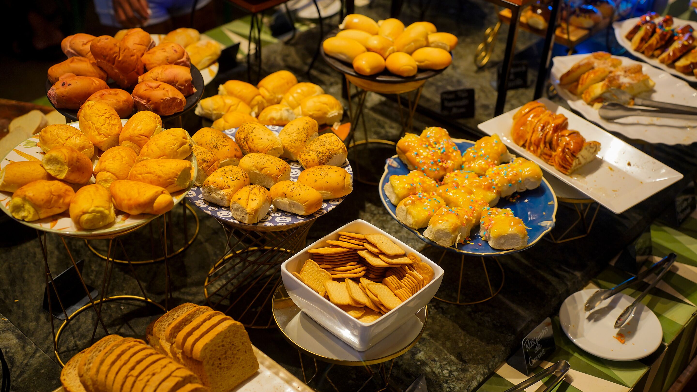 A buffet with various baked goods including rolls, pastries, and bread.