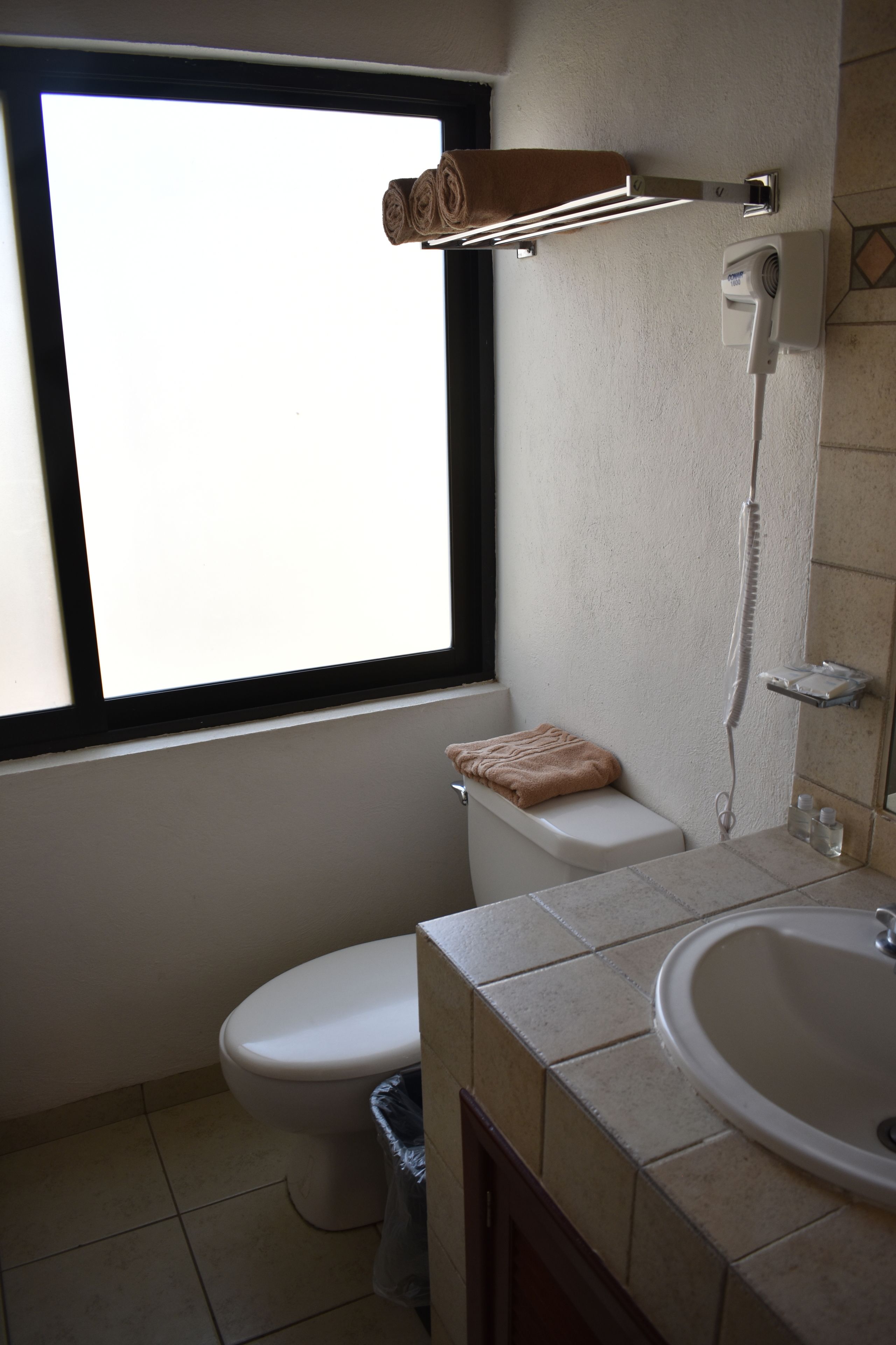 A bathroom with a toilet, sink, and a window.