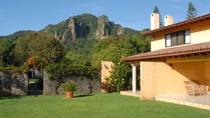 Ein Haus mit einer Terrasse, einer Steinmauer und einem Berg im Hintergrund.
