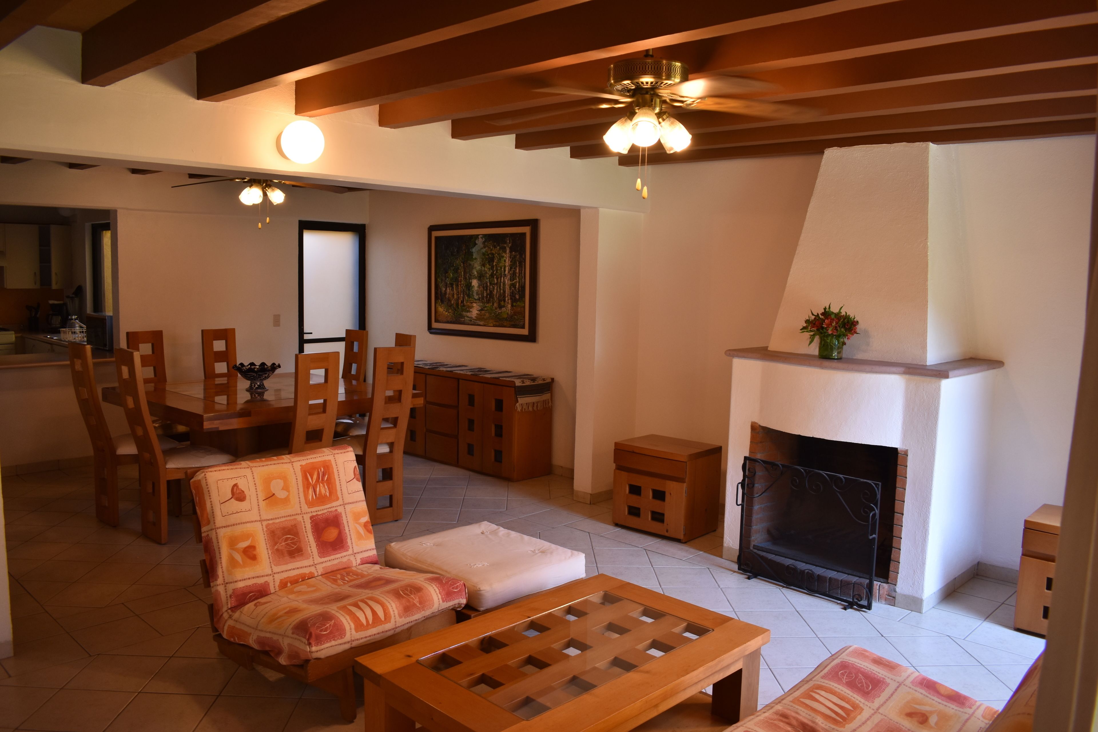 Una sala de estar con chimenea, muebles de madera y un comedor con sillas y una mesa.