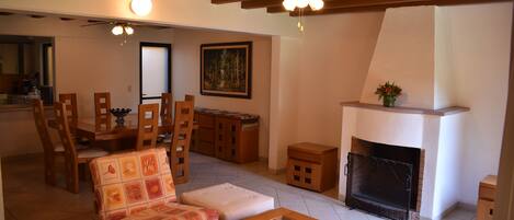 Una sala de estar con chimenea, muebles de madera y un comedor con sillas y una mesa.