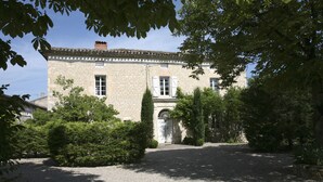 A stone building with a gravel driveway and a small garden area. - Chambres d'hôtes - Les Vents Bleus (Donnazac)