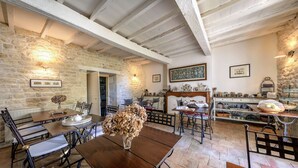A rustic dining area with stone walls, wooden beams, and a variety of dining ware. - Chambres d'hôtes - Les Vents Bleus (Donnazac)