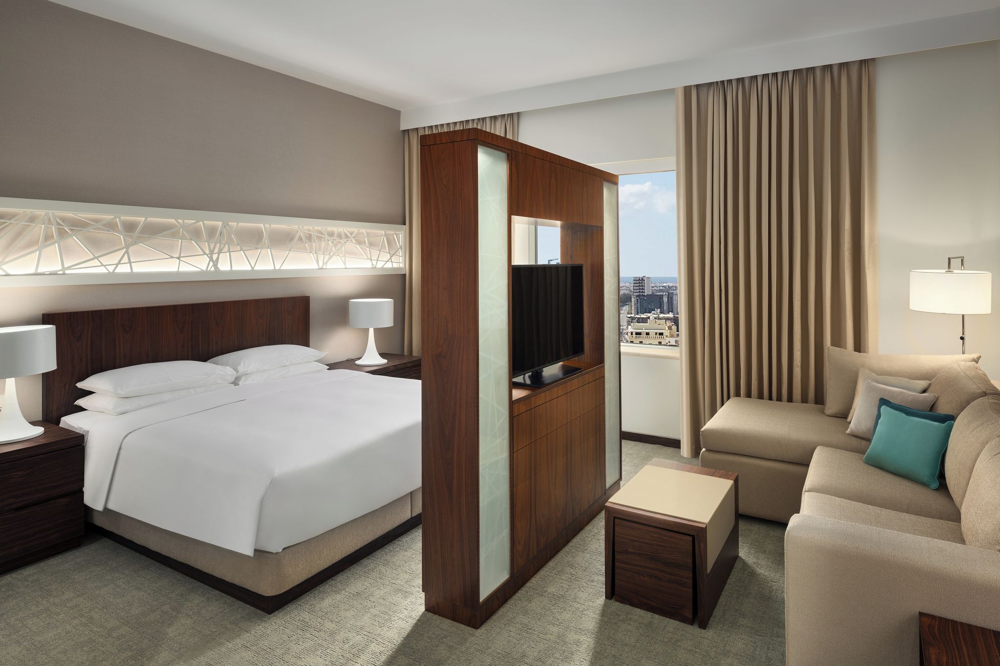 A hotel room with a bed, a TV, a sofa, and a desk.