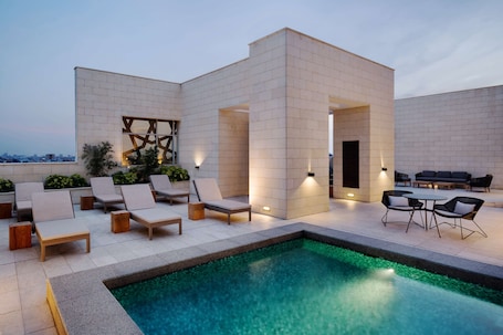 Una piscina al aire libre, sombrillas, sillones reclinables de piscina