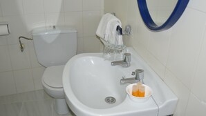 Un bany amb un vàter blanc, un lavabo amb mirall i una tovallola penjada a la paret.