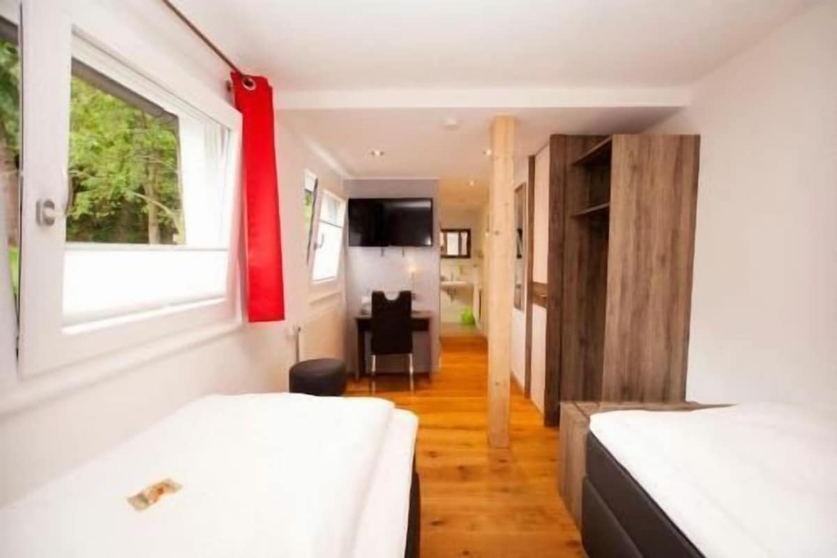 A hotel room with a bed, a desk, and a view of the outdoors.