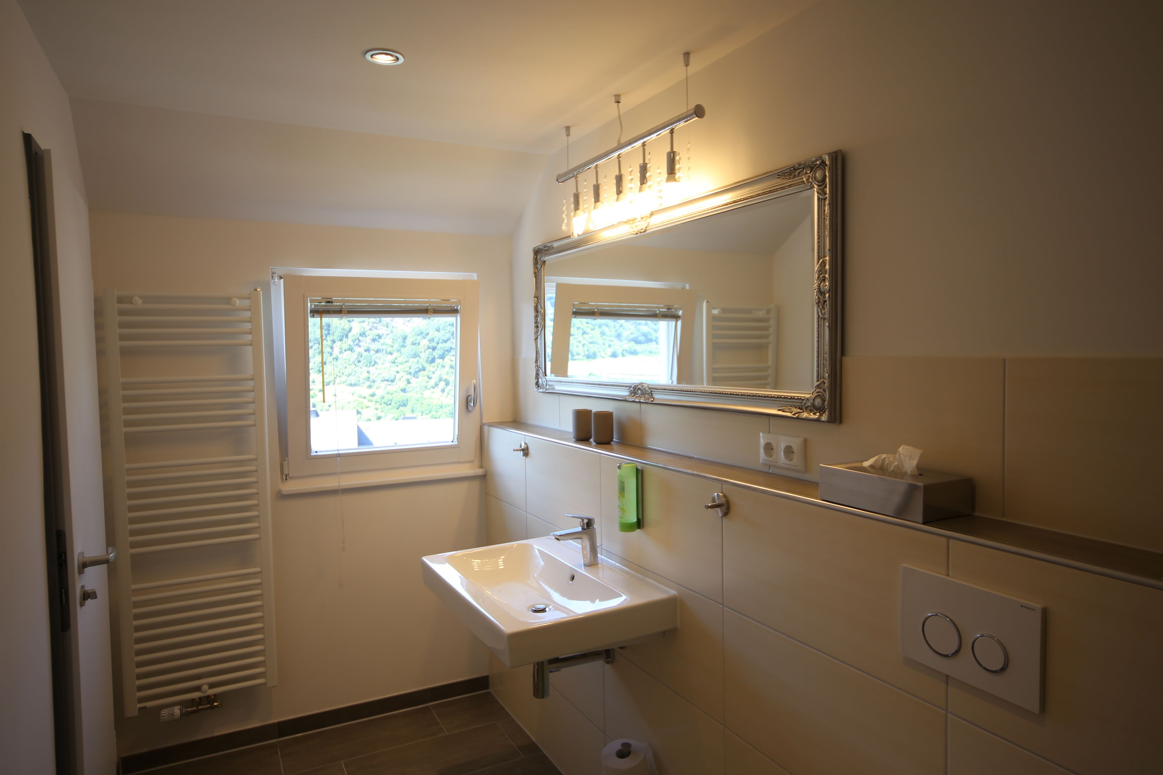 A bathroom with a white sink, a mirror, a window, and a towel rack.