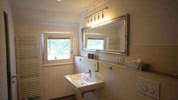 A bathroom with a white sink, a mirror, a window, and a towel rack.