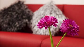 Een rode bank met twee roze bloemen in vazen.