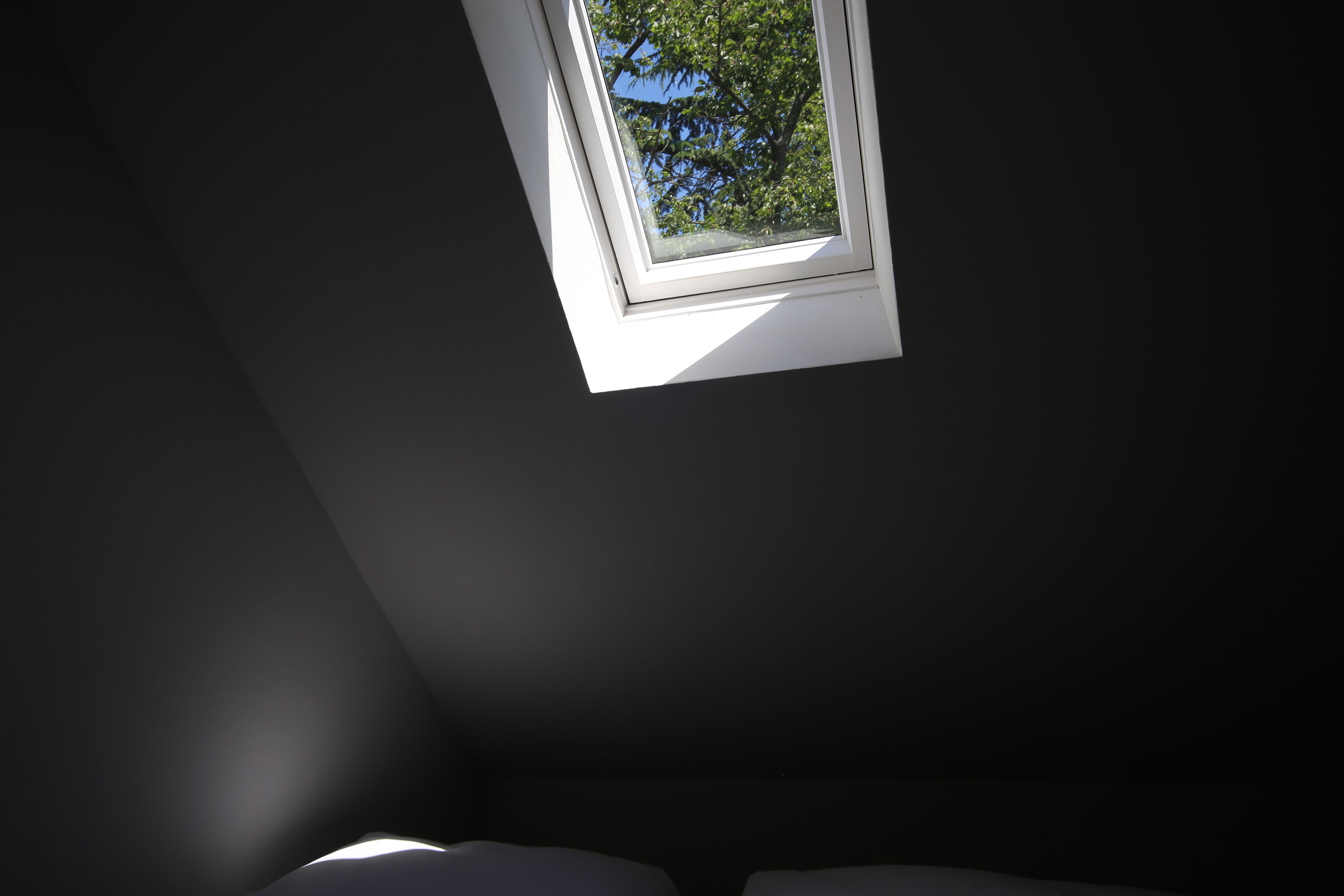Een dakraam in een kamer met een donker plafond en muren.