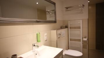 A bathroom with a white sink, mirror, and toilet.