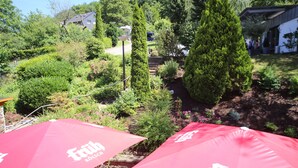 A garden area with red umbrellas labeled "Früh KÖLSCH" and a stone staircase leading up to a building. - Hotel Vintage am Bundesbank Bunker (Cochem)