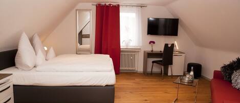 Un dormitorio con una cama, un escritorio, una silla, un televisor y una cortina roja.