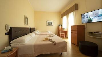 Una camera d'albergo con due letti, una scrivania, una televisione e un armadio.