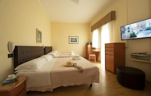 A hotel room with two beds, a desk, a television, and a wardrobe. - Hotel Milano (Cesenatico)