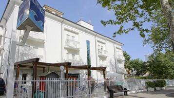 Un edificio bianco con balconi e un cartello con scritto Milano Hotel.