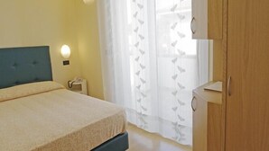 A bedroom with a bed, bedside table, and a wardrobe. - Hotel Milano (Cesenatico)
