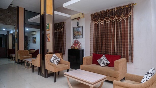 A spacious living area with beige sofas, a wooden coffee table, and patterned cushions. - RedDoorz Plus @ Grand Populer Hotel (Makassar)