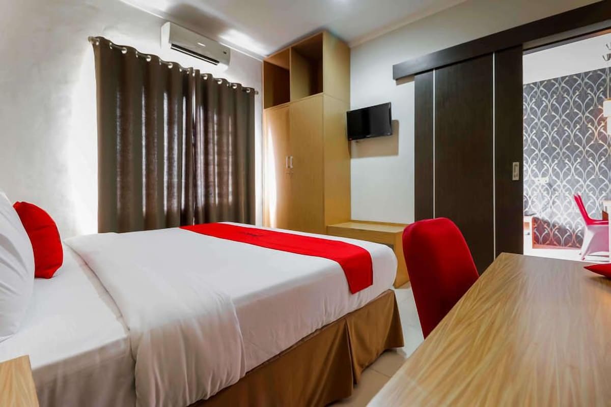A hotel room with two beds, a wooden table, a TV, and a wardrobe.