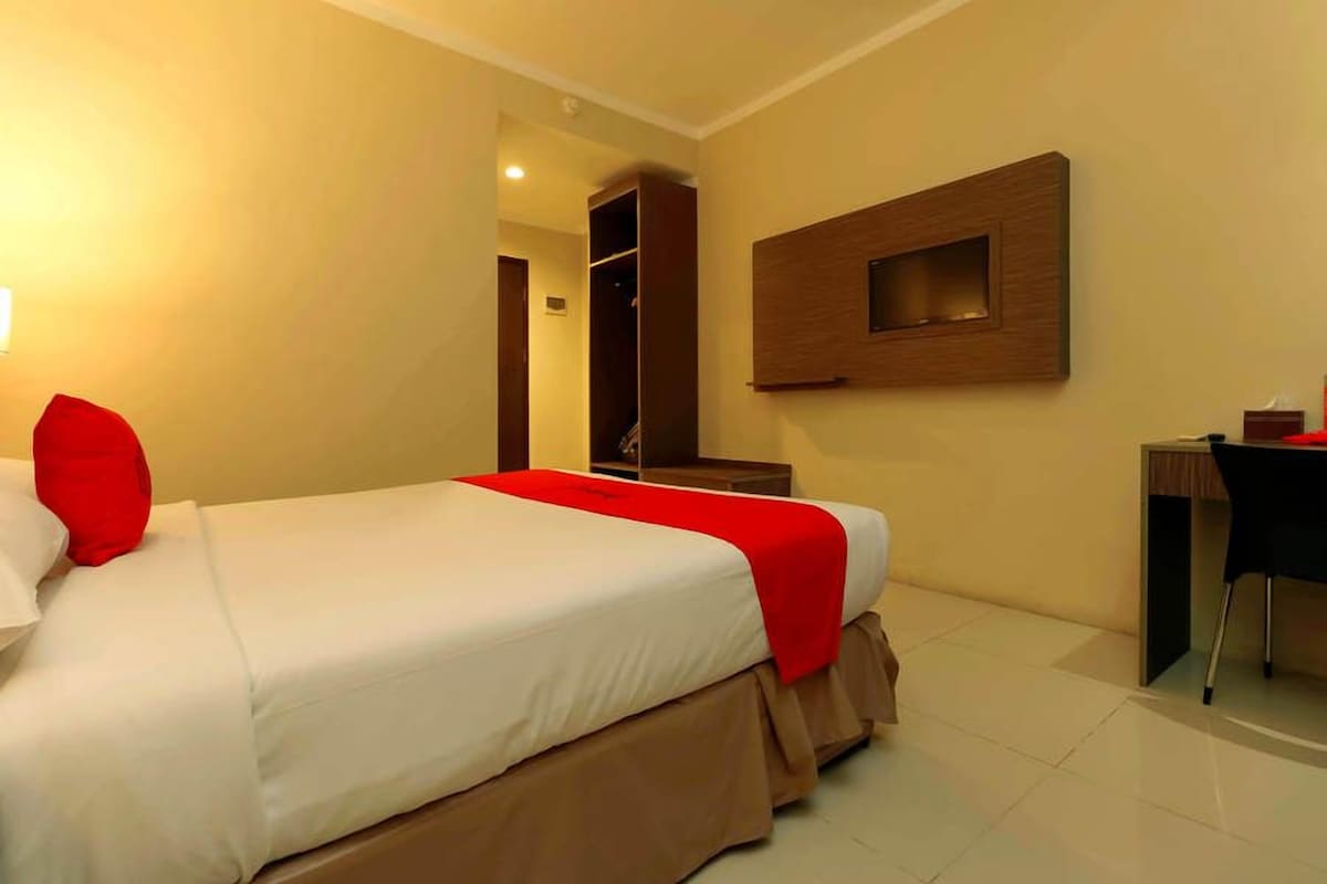 A hotel room with a bed, a desk, and a wardrobe.