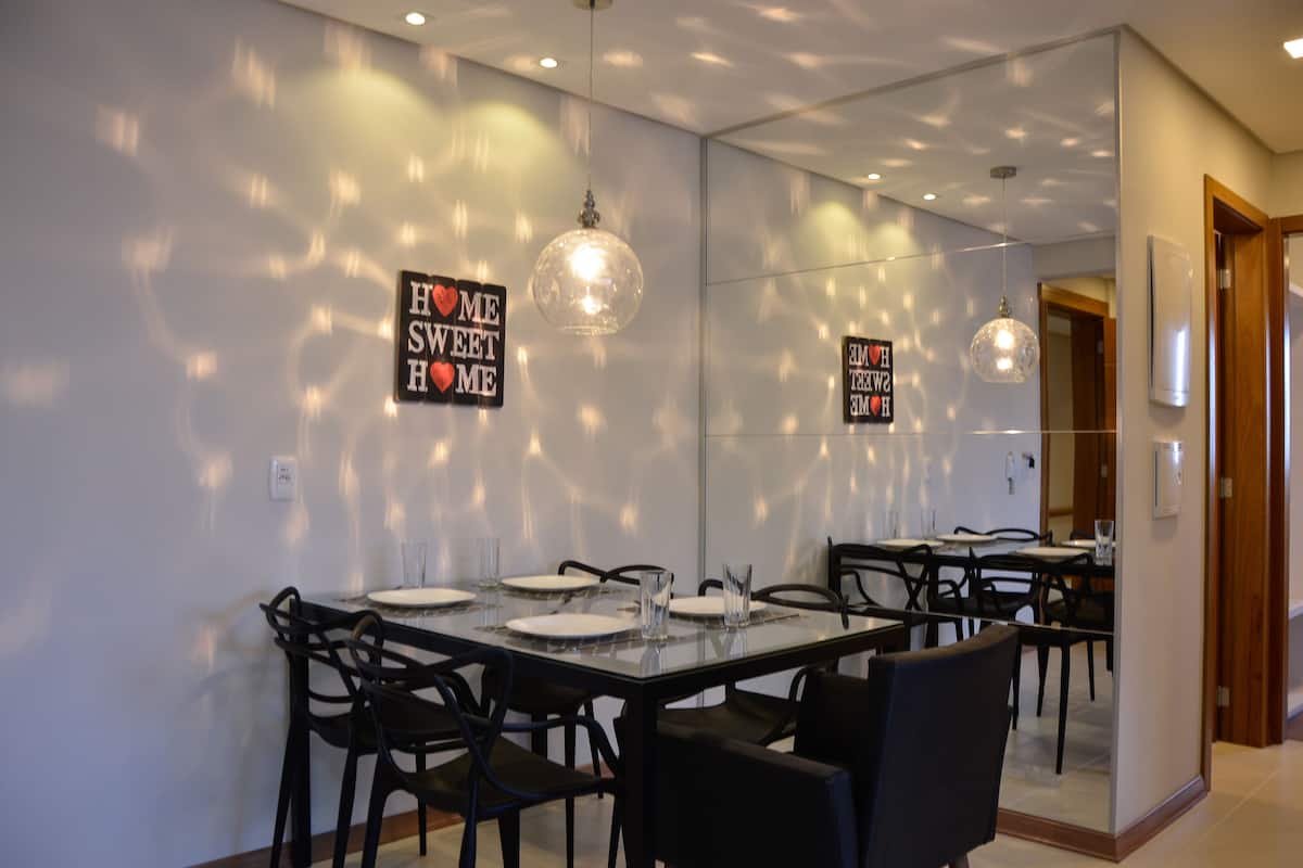 A modern dining area with a glass table, black chairs, and pendant lights.