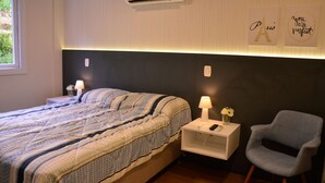 Un dormitorio con cama, mesita de noche, lámpara, silla y adornos en la pared.