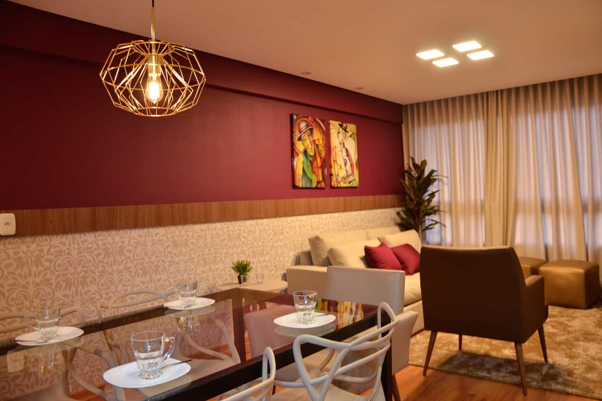 A dining area with a glass table, chairs, and a hanging light fixture.
