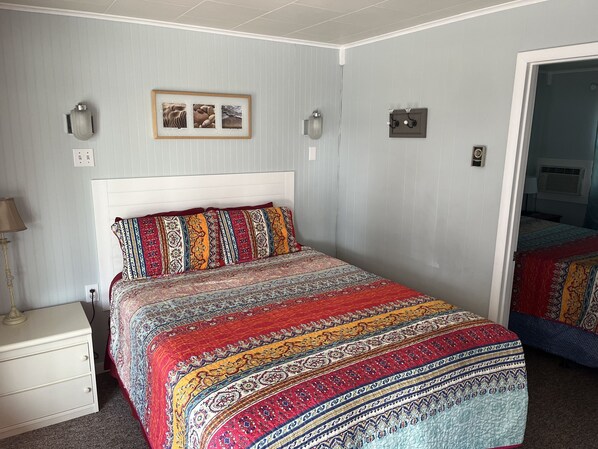 Un dormitorio con una cama grande, una mesita de noche, una lámpara y un cuadro en la pared.
