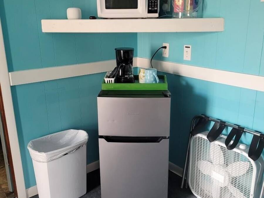 Una kitchenette compacta con microondas, cafetera y un pequeño cubo de basura.