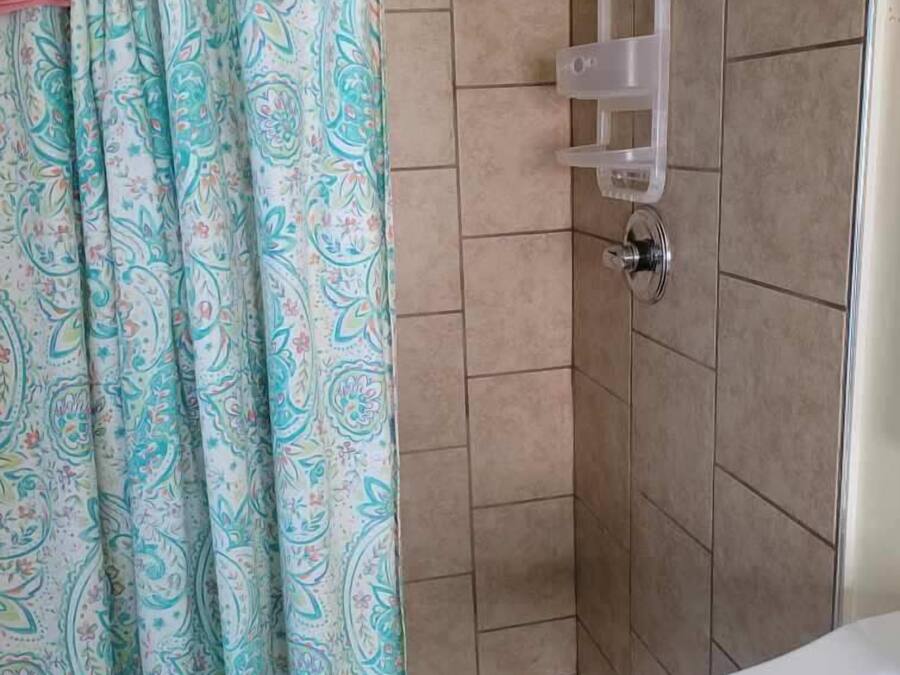 A bathroom with a shower, tiled walls, a shower caddy, and a bathtub.