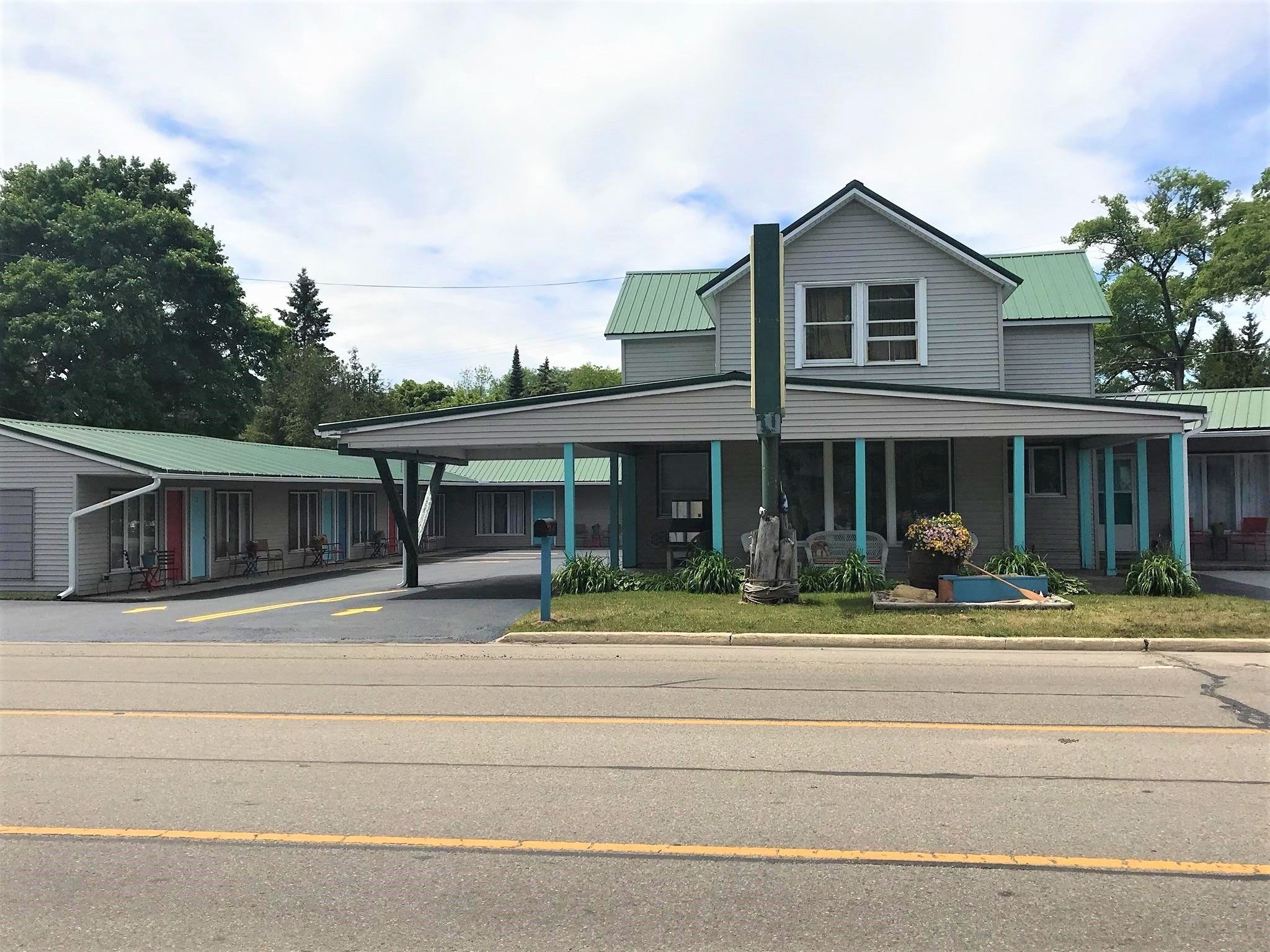 A motel with a covered parking area and a two-story building with a green roof.