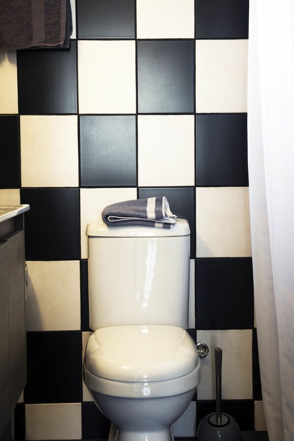 A toilet with a black and white checkered tile backsplash.