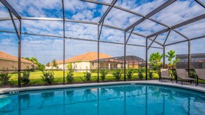 Una piscina con un recinto in vetro, circondata da un prato e degli edifici.